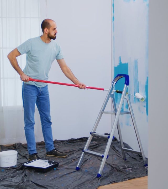 masaking-blue-paint-with-roller-brush-dipped-white-paint-handyman-renovating-apartment-redecoration-home-construction-while-renovating-improving-repair-decorating (1)